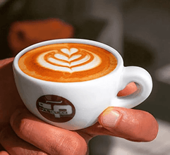 O ceașcă de cafea espresso cu artă latte, servită într-o cană albă, captivând un moment de savurare.